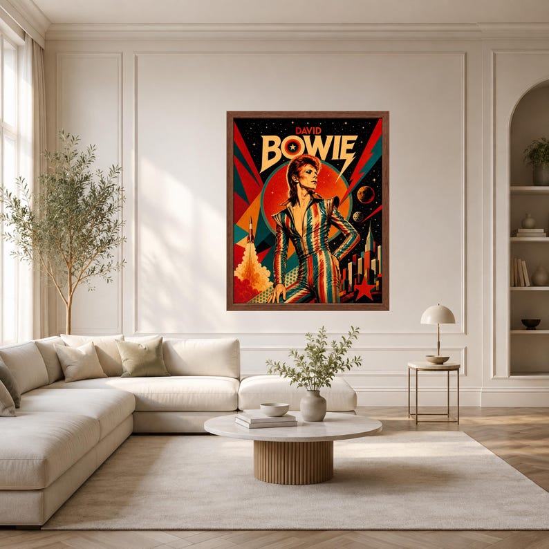 May include: A framed wall art print featuring a stylised illustration of David Bowie in a striped jumpsuit. The artwork includes a rocket, planets, and a red star against a dark background with bold geometric shapes in red, teal, and yellow.