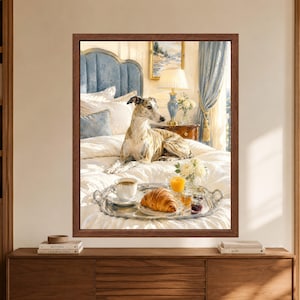 Framed greyhound wall art showing a brindle whippet resting on a white bed beside a silver breakfast tray with coffee, croissant, orange juice, preserves and flowers in a soft blue bedroom.