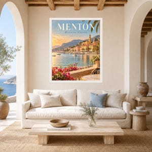 May include: A framed wall art print featuring a scenic view of Menton on the French Riviera. The image displays a coastal town with colorful buildings, a blue sea, and pink flowers in the foreground. The text reads MENTON Riviera Stories.