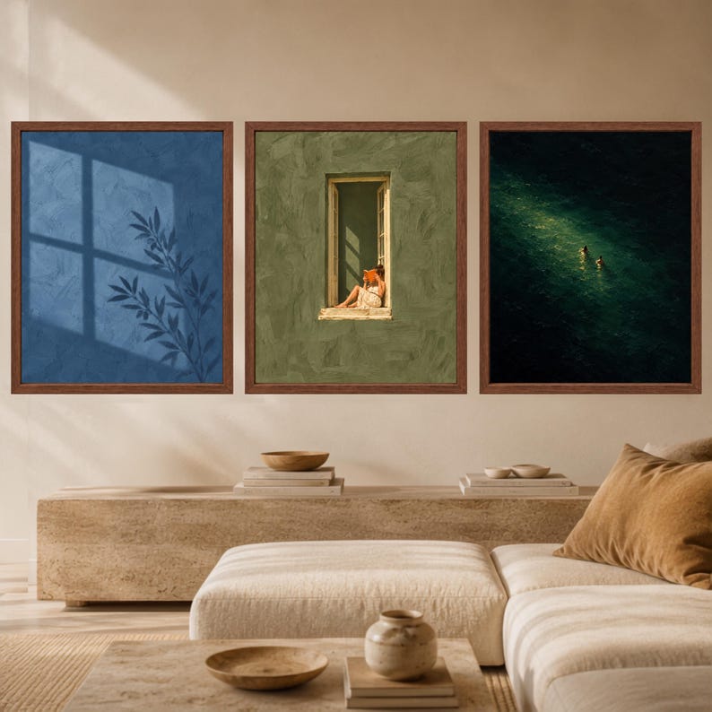 May include: A set of three square wall art prints in dark wood frames. The left print shows a blue wall with a plant shadow. The center print depicts a person sitting in a window frame. The right print shows two figures swimming in dark water.