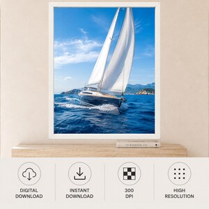 Op de afbeelding: Een ingelijste muurkunstprint met een donkerblauwe zeilboot met witte zeilen die over diepblauw oceaanwater vaart onder een helderblauwe lucht met lichte wolken. De zeilboot cre&euml;ert een wit kielzog terwijl deze naar verre rotsachtige heuvels vaart.