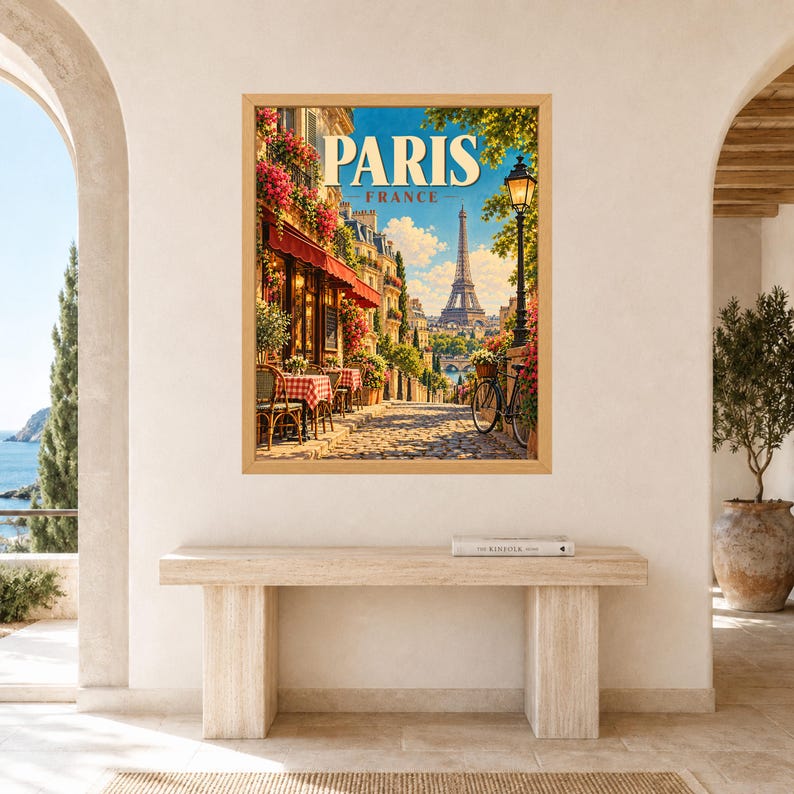 May include: A framed wall art print featuring a vibrant street scene in Paris, France. The image displays a cobblestone path, a cafe with red awnings and checkered tablecloths, a bicycle, and the Eiffel Tower under a bright blue sky.