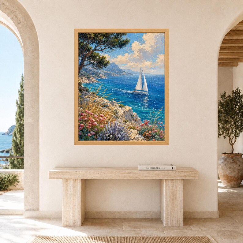 May include: A framed rectangular wall art print featuring a coastal landscape with a white sailboat on deep blue water, a rocky shoreline with tall grasses, pink and purple wildflowers, and a large tree under a bright blue sky with white clouds.