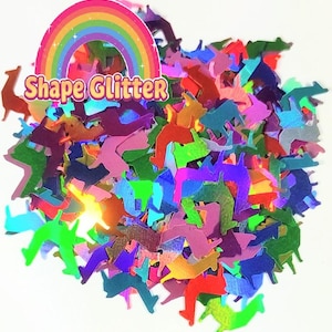 May include: A pile of colorful iridescent glitter shaped like llamas. The glitter is scattered on a white background. The text "Shape Glitter" is visible in the image.