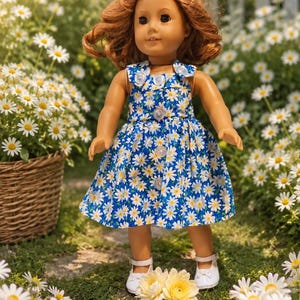 May include: A doll with shoulder-length wavy brown hair wearing a sleeveless blue dress featuring a white daisy pattern and a front button closure. The doll has light skin, brown eyes, and is wearing white shoes with a strap across the top.