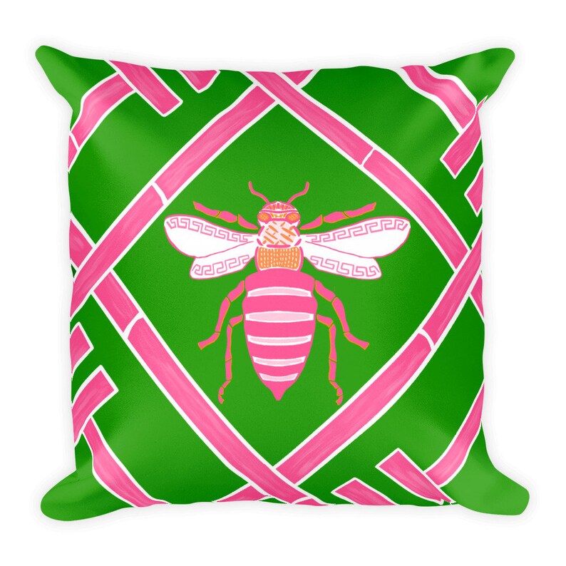 May include: A green and pink throw pillow with a pink and white bee design. The bee has a geometric pattern on its wings.
