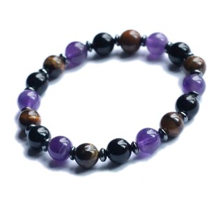 May include: A beaded bracelet with alternating black, brown, and purple beads. The bracelet is made of natural stones.