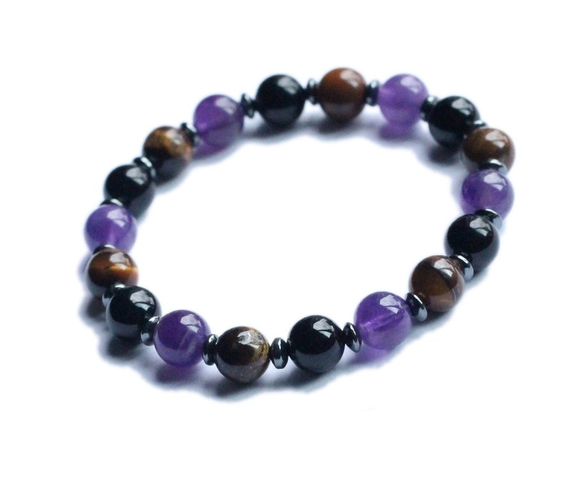May include: A beaded bracelet with alternating black, brown, and purple beads. The bracelet is made of natural stones.