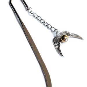 May include: A silver metal bookmark with a chain and a charm. The charm is a golden snitch with silver wings. The bookmark is a long, flat piece of metal with a curved top.