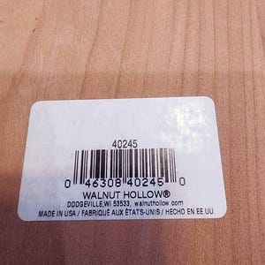 May include: A white rectangular label with a barcode and the text "WALNUT HOLLOW&reg;" printed in black. The label also includes the text "MADE IN USA / FABRIQUE AUX &Eacute;TATS-UNIS / HECHO EN EE.UU." on a light brown wooden surface.