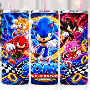 May include: A cylindrical tumbler with a pink straw featuring a vibrant graphic print of Sonic the Hedgehog, Tails, Knuckles, Shadow, and Amy Rose against a background of blue and red lightning, golden rings, and a checkered racing flag pattern.