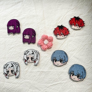 May include: A collection of seven embroidered patches featuring chibi-style anime character heads with various hair colors including purple, red, white, and blue, alongside a small, pink, five-petaled fabric flower with a white center.