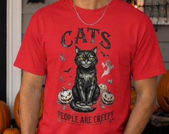Könnte beinhalten: Ein rotes Kurzarm-T-Shirt mit einer Grafik eines schwarzen Katers mit gelben Augen, umgeben von kleinen Kürbissen, Fledermäusen und einem Geist. Der Text "CATS" steht darüber und "PEOPLE ARE CREEPY" ist darunter aufgedruckt.