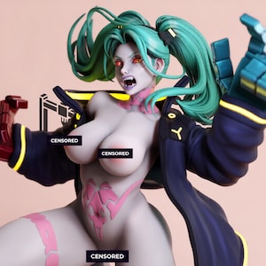 May include: A collectible figurine featuring a character with teal hair in pigtails, orange eyes, and bared teeth. The figure wears a dark blue jacket with yellow accents and displays pink graphic markings on the skin. Black censored bars cover parts.