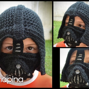 May include: A black crocheted hat with a Darth Vader mask design. The hat has a pointed top and a black crocheted mask with a silver detail. The hat is worn by a child.