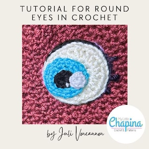 May include: A crochet tutorial titled TUTORIAL FOR ROUND EYES IN CROCHET by Juli Voncannon. The image features a circular eye motif with a white sclera, a bright blue iris, a black pupil, and a small white highlight, stitched onto a maroon background.