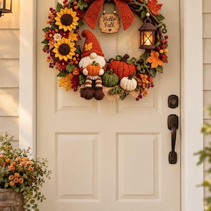 Könnte beinhalten: Ein dekorativer Herbstkranz mit einer großen rostfarbenen Schleife, Sonnenblumen und einem zentralen Wichtel, der einen Kürbis hält. Der Kranz enthält ein Holzschild mit dem Text Hello Fall, eine kleine hängende Laterne und gehäkelte Kürbisse.