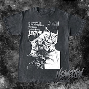 Könnte beinhalten: Ein anthrazitfarbenes Kurzarm-T-Shirt mit einem weißen Grafikdruck einer gehörnten Kreatur. Der Text lautet: "No Good without Evil. No Love without Hate. No Innocence without Lust. I am Darkness." sowie das Wort "LEGEND" in einer stilisierten Schrift.