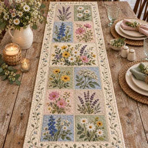 Può includere: Un runner da tavola trapuntato rettangolare caratterizzato da una serie di pannelli quadrati, ciascuno ricamato con vari fiori di campo colorati tra cui lavanda, margherite, cosmee e fiori gialli, bordato da un delicato motivo a tralci su fondo crema.