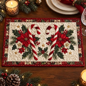 Può includere: Una tovaglietta trapuntata rettangolare con un centro color crema decorato da due bastoncini di zucchero a strisce rosse e bianche, stelle di Natale rosse, foglie di agrifoglio verdi e piccole bacche rosse. Il bordo ha un motivo patchwork.