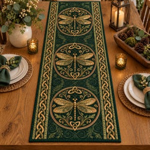 Puede incluir: Un camino de mesa rectangular largo en color verde bosque profundo con tres medallones circulares, cada uno con una ilustración detallada de una libélula con alas doradas y verdes, rodeado de bordes con nudos celtas.