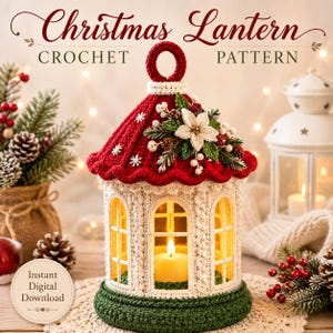 Può includere: Un modello di lanterna natalizia all'uncinetto con tetto rosso e fiocchi di neve bianchi, corpo color crema con finestre ad arco e base verde scuro. La parte superiore è decorata con una stella di Natale bianca, pino e bacche.