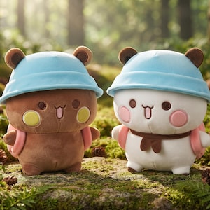 May include: Two plush bear toys, one brown and one white, each wearing a light blue bucket hat and a small pink backpack. Both bears feature round ears, dark brown eyes, a small mouth with a tongue sticking out, and round cheek patches.