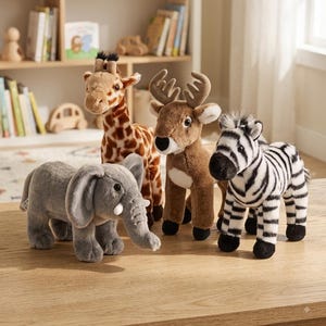 May include: A collection of four plush animal toys standing on a wooden surface. The set includes a gray elephant, a brown and tan giraffe with spots, a brown deer with antlers, and a black and white striped zebra, all featuring soft textures.