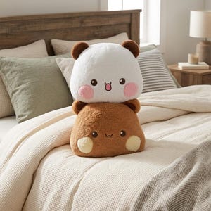 May include: A plush toy featuring a white bear with pink cheeks stacked on top of a brown bear with cream-colored cheeks. Both bears have small round ears, dark eyes, and simple embroidered mouths, creating a soft, layered stuffed animal design.