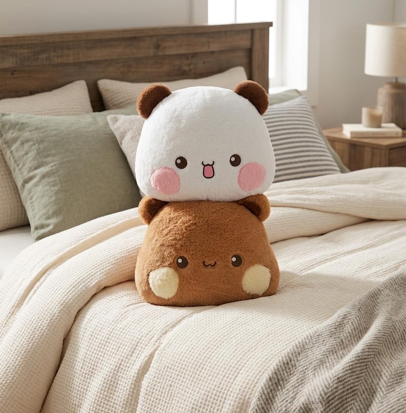May include: A plush toy featuring a white bear with pink cheeks stacked on top of a brown bear with cream-colored cheeks. Both bears have small round ears, dark eyes, and simple embroidered mouths, creating a soft, layered stuffed animal design.