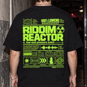 May include: A black short-sleeved t-shirt featuring a large, bright neon green graphic on the back. The design includes the text "RIDDIM REACTOR" and "100% LOWEND" alongside various technical diagrams, sound wave patterns, and symbols.