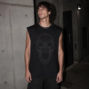 May include: A black sleeveless shirt featuring a large, dark grey graphic print of a skull with an open mouth on the front. The garment has a crew neckline and a relaxed fit, constructed from a solid black fabric with a tonal skull illustration.