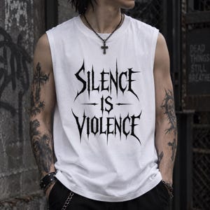 Op de afbeelding: Een wit mouwloos hemd met de zwarte tekst Silence is Violence in een scherp, gotisch lettertype in het midden op de borst. Het kledingstuk heeft een ronde halslijn en brede armopeningen, wat zorgt voor een strak en contrastrijk uiterlijk.