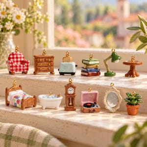 Puede incluir: Una colección de dijes en miniatura con artículos para el hogar, que incluyen un sillón a cuadros rojos y blancos, una cómoda de madera, una tostadora azul, una pila de libros, una lámpara verde, una mesa redonda, una cama, una bañera, un reloj, un tocadiscos, un espejo y una planta.