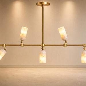 May include: A linear chandelier featuring a horizontal brass rod suspended from a central vertical stem. The fixture holds five cylindrical light shades made of white marbled stone, each attached to the rod with adjustable brass swivel joints.