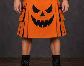Kilt utilitário masculino de Halloween com estampa de abóbora, cor laranja escocesa, com bordado frontal de rosto de abóbora preto.