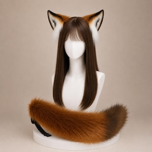 Può includere: Una parrucca lunga e liscia color marrone con frangia su una testa di manichino, con orecchie da volpe in peluche con pelo bianco e arancione. Una lunga e soffice coda di volpe in pelliccia sintetica arancione e marrone è posizionata sotto.