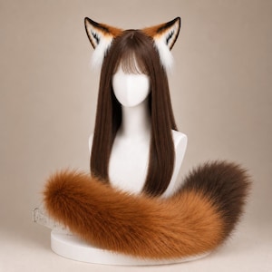 May include: A long, straight brown wig with bangs displayed on a white mannequin head. The wig features attached fox ears with orange, white, and black fur. A large, fluffy, multi-toned orange and brown faux fur fox tail is positioned in front.