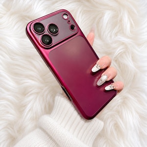 May include: A deep magenta smartphone case with a matte finish, featuring a metallic-toned camera module cutout with three circular lens openings and a smaller circular flash opening at the top, designed to fit a modern mobile device.