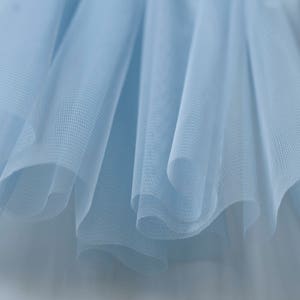May include: Close-up of light blue tulle fabric with a soft, delicate texture.