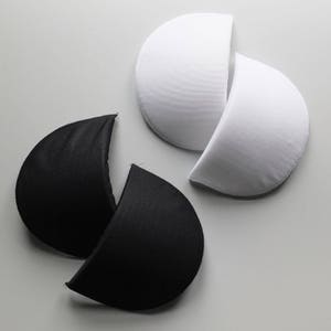 Puede incluir: Dos pares de almohadillas para sujetador, una negra y una blanca. Las almohadillas tienen forma de semicírculo y están hechas de un material suave y acolchado.