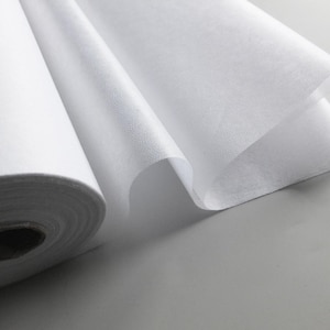 May include: A roll of white interfacing fabric, a type of fusible material used in sewing and quilting projects.