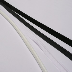 May include: Three different types of white and black cord, with a stitched seam down the centre of each.