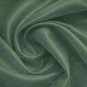 May include: Close-up of a flowing, sage green fabric. The material has a silky sheen and is draped in soft folds, creating a sense of movement and texture. The fabric's colour is a muted, earthy green, with highlights and shadows.