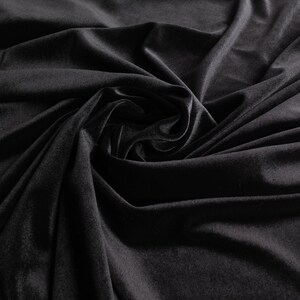 May include: Black velvet fabric with a soft, smooth texture. The fabric is draped and folded, creating a luxurious and elegant look.