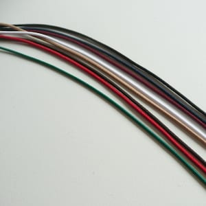 May include: Assortment of 10 colours of elastic cord, including green, red, brown, white, beige, burgundy, navy, black, and two shades of grey.