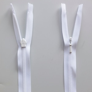 May include: Two white zipper pulls with silver sliders. The zipper pulls are open and closed.