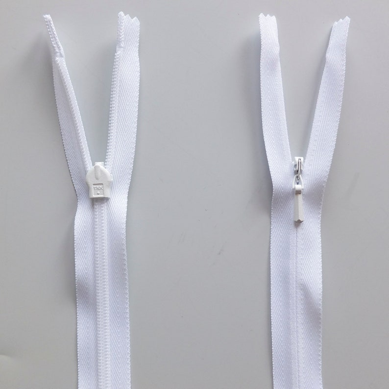 May include: Two white zipper pulls with silver sliders. The zipper pulls are open and closed.