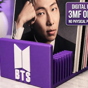 Pode incluir: Um suporte de armazenamento roxo impresso em 3D para discos de vinil ou mídia, com um logotipo branco do BTS na frente. O suporte possui divisórias verticais para manter os itens na vertical. Indica 3MF ONLY NO PHYSICAL PRODUCT.