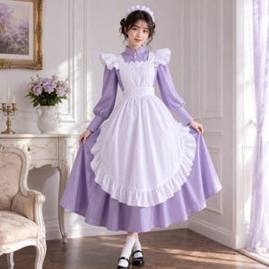 May include: A long-sleeved lavender dress featuring a high collar and a white apron with a ruffled hem. The outfit includes a matching white ruffled headband. The dress has a fitted bodice, a full skirt, and white ruffled shoulder accents.
